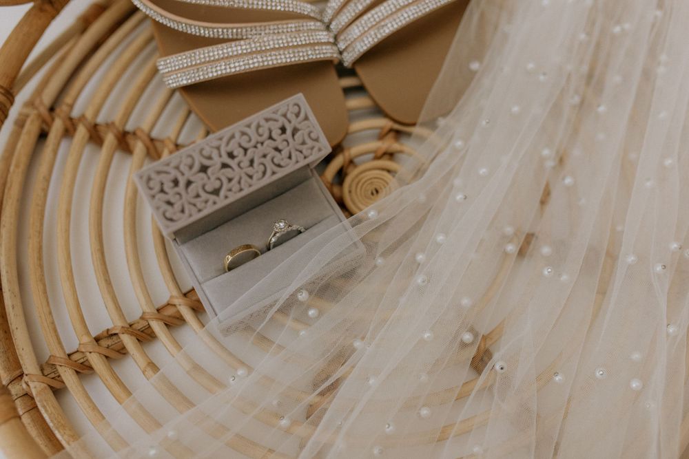Wedding rings displayed in a decorative box alongside flowing tulle fabric.