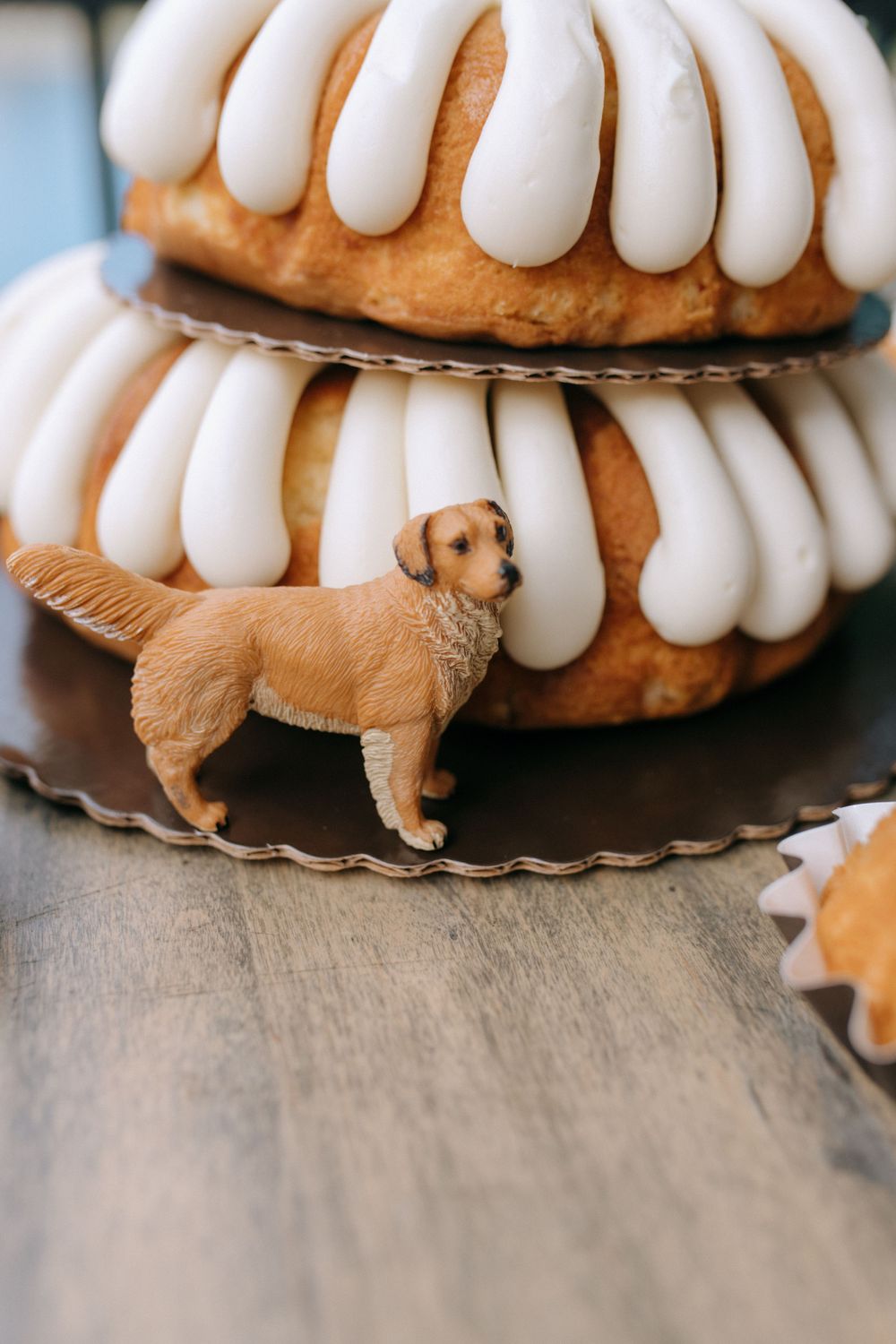 A decorative golden retriever figurine sits between white-frosted bundt cakes on dark plates.