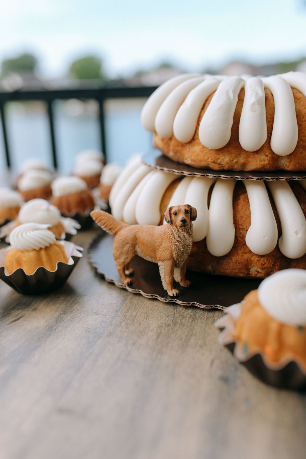 Golden retriever figurine displayed with stacked bundt cakes and mini desserts on wooden table.