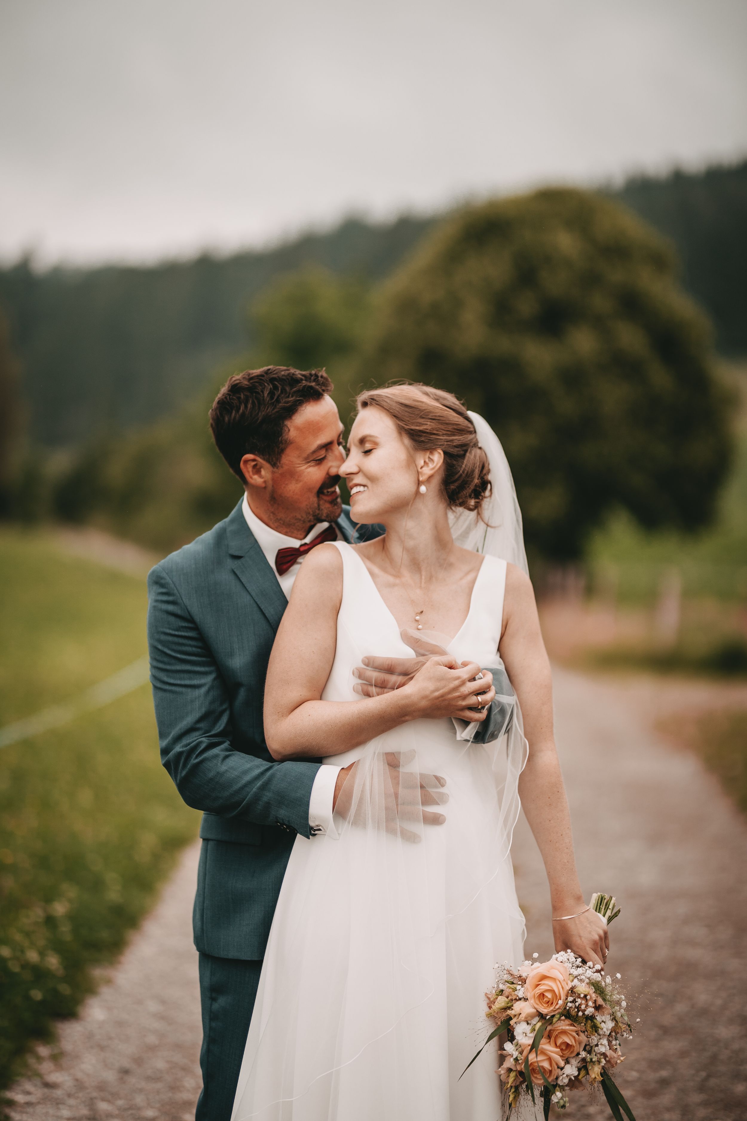 Romantic outdoor wedding scene with couple in white dress and dark suit.