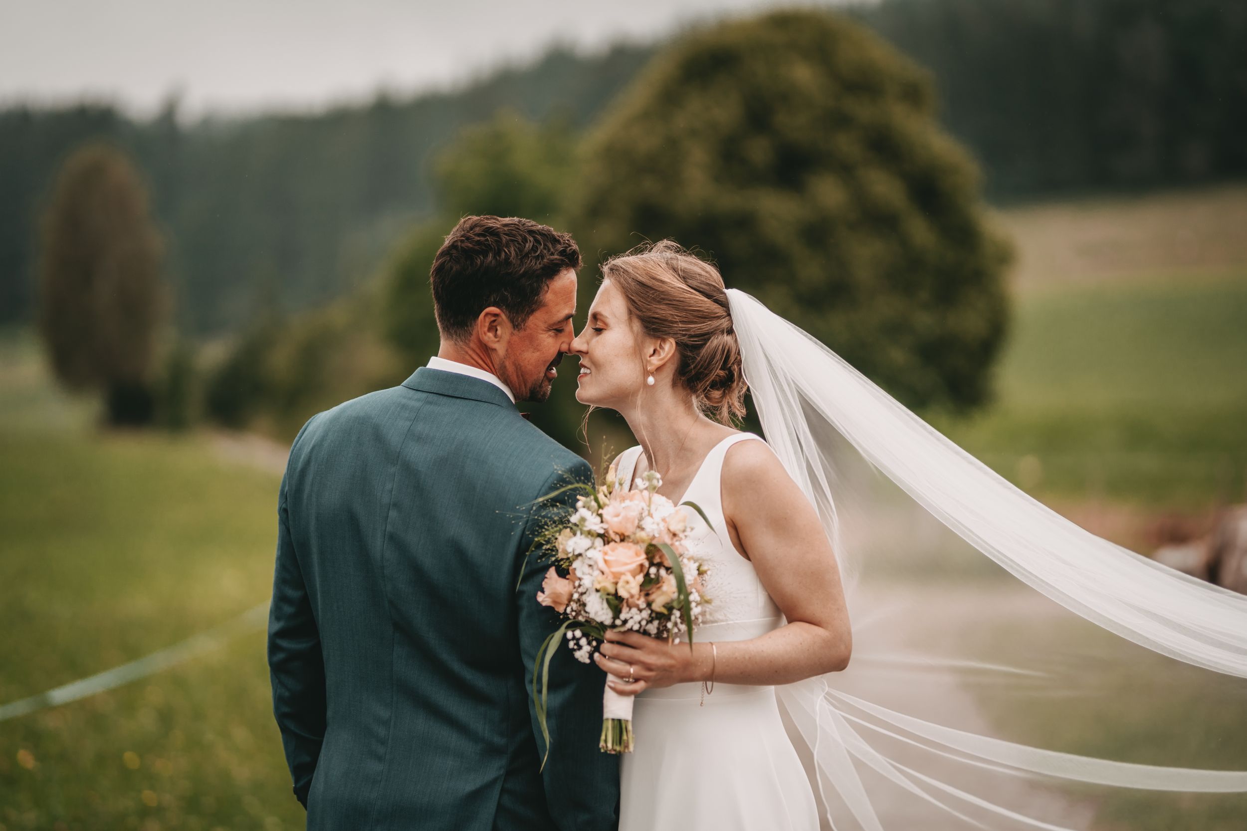 Romantic wedding portrait in outdoor rural setting with flowing veil.