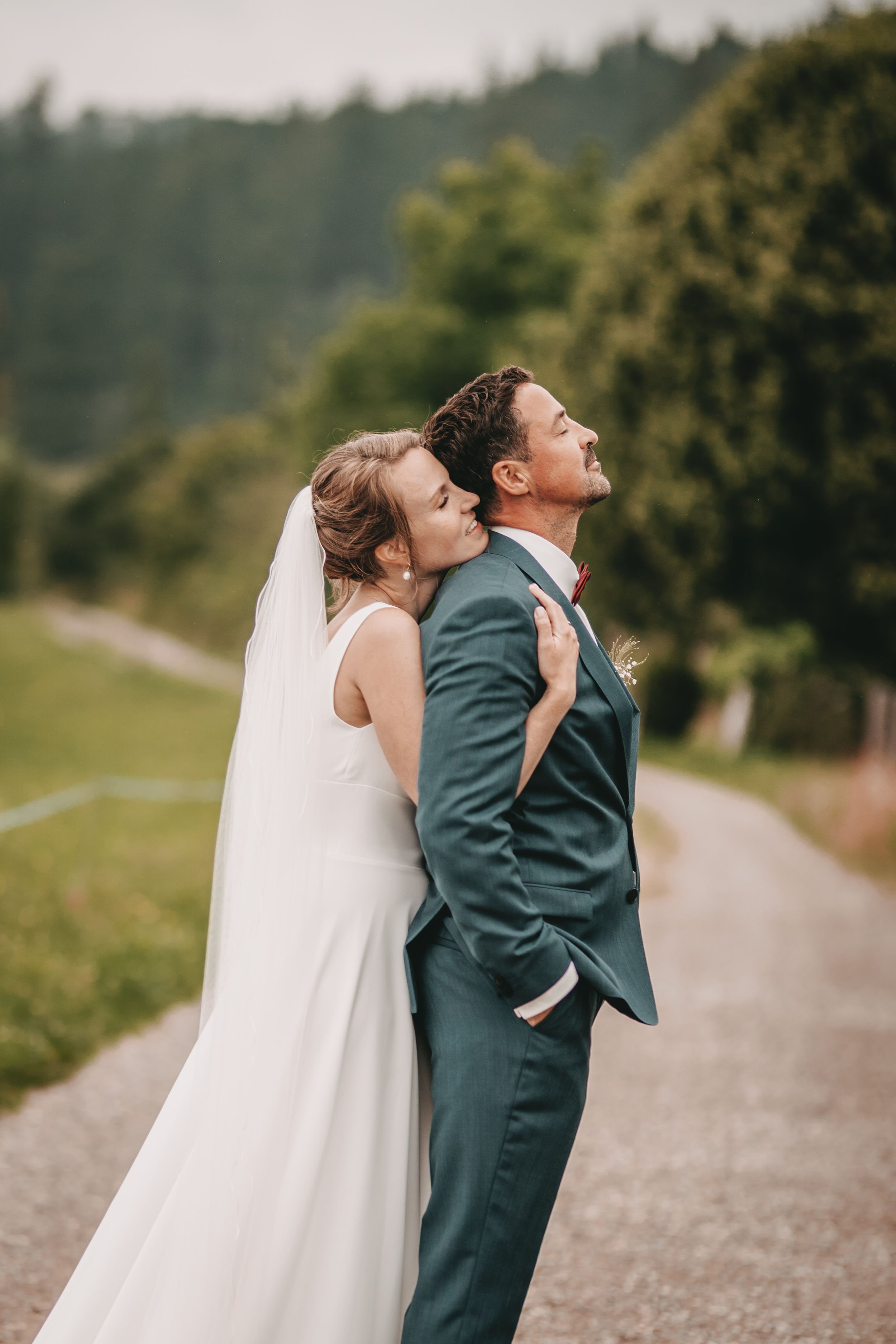 Romantic wedding couple embracing on a mountain path surrounded by nature.