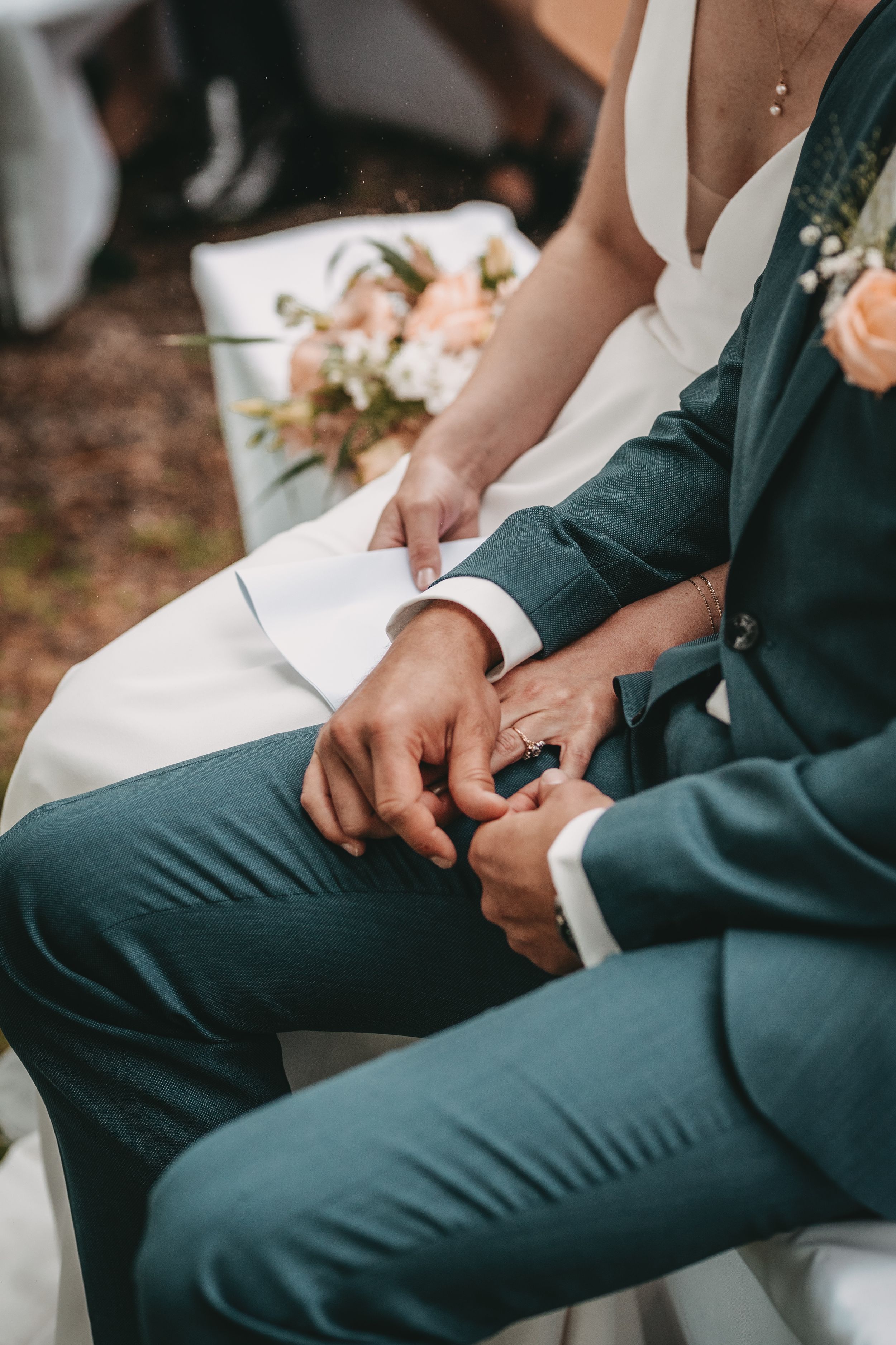 Detail shot of wedding attire showing teal suits and white dress during ceremony.