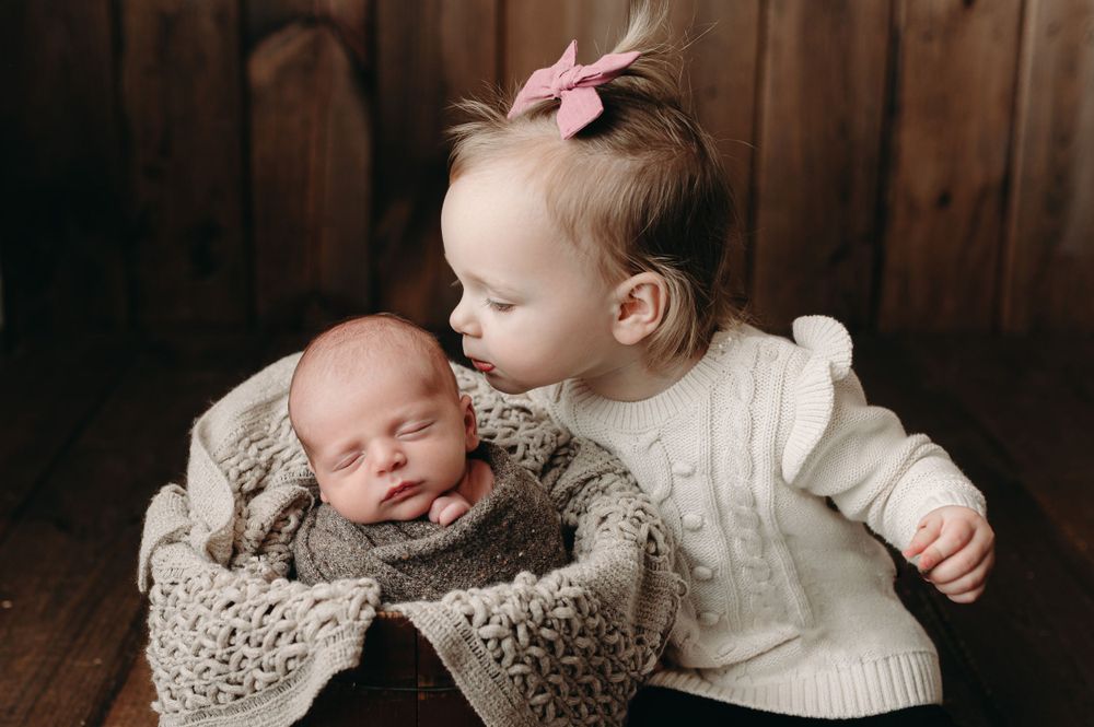 Newborn studio photographer young sibling photo giving kisses bloomington normal Illinois