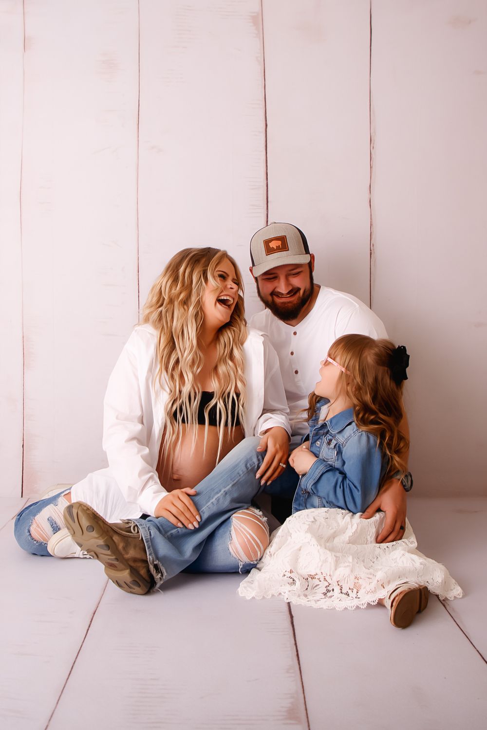 A happy family sitting together on white wooden floors sharing a joyful moment.