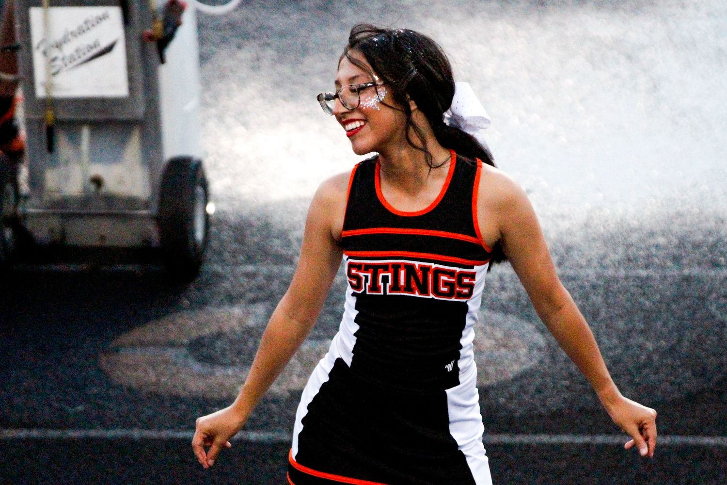 Cheerleader performing in red and black uniform during outdoor event.