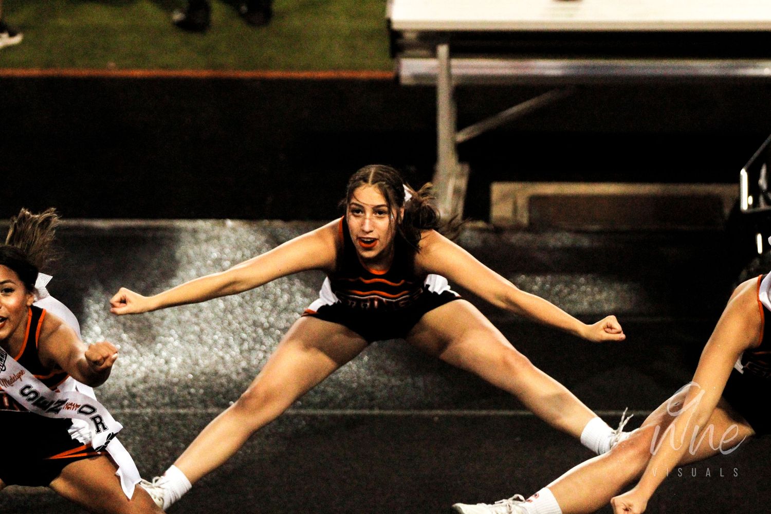 Cheerleaders performing splits during an energetic routine on stage.