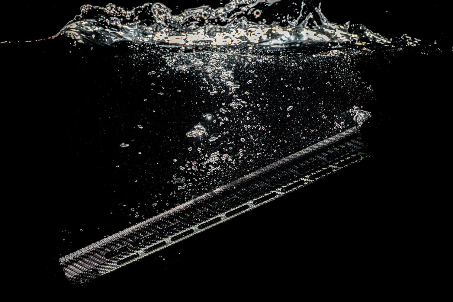 Silhouetted rifle handguard in a tank of water with bubbles