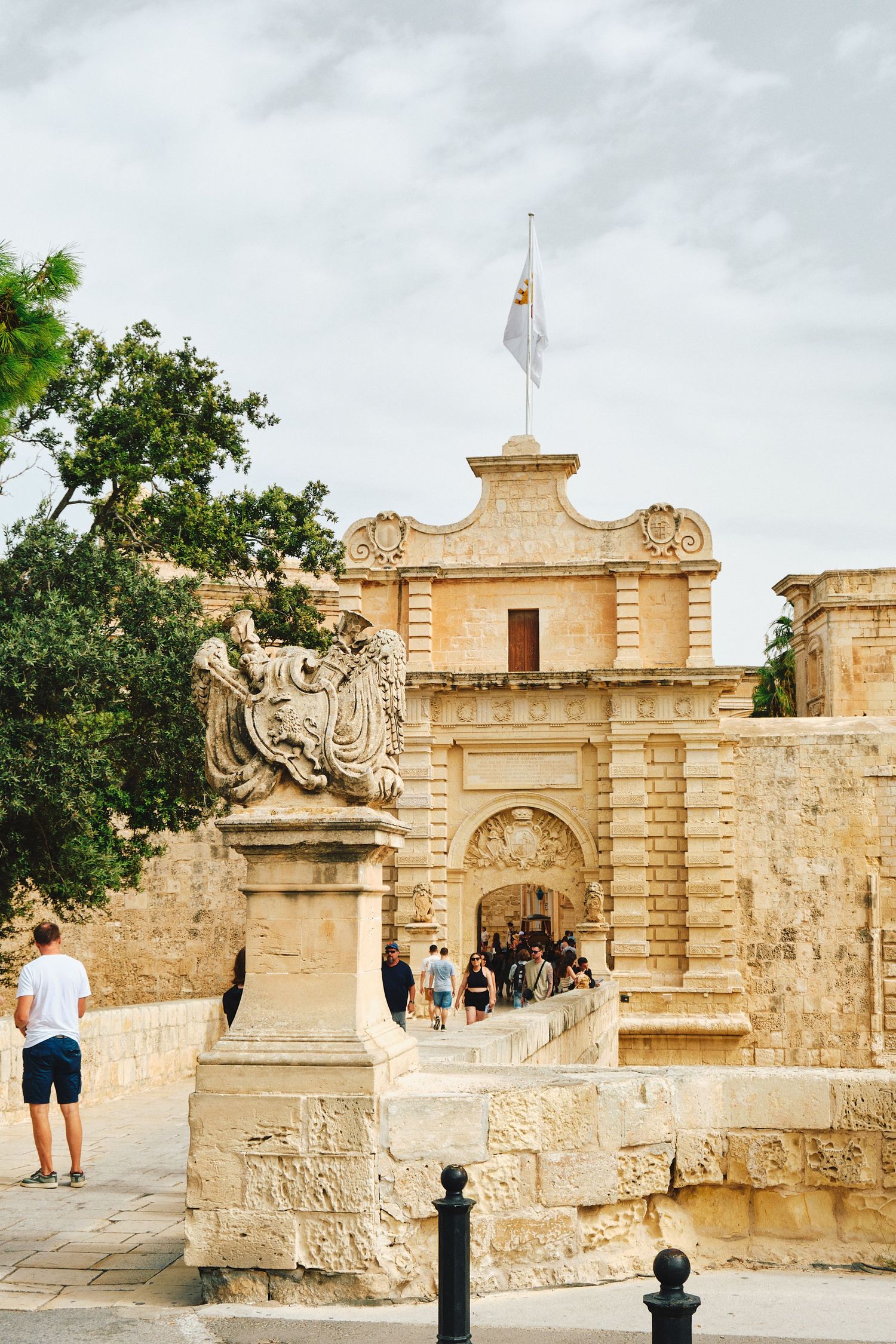 Ancient stone entrance gate to Mdina with ornate architectural details and statues in Malta.