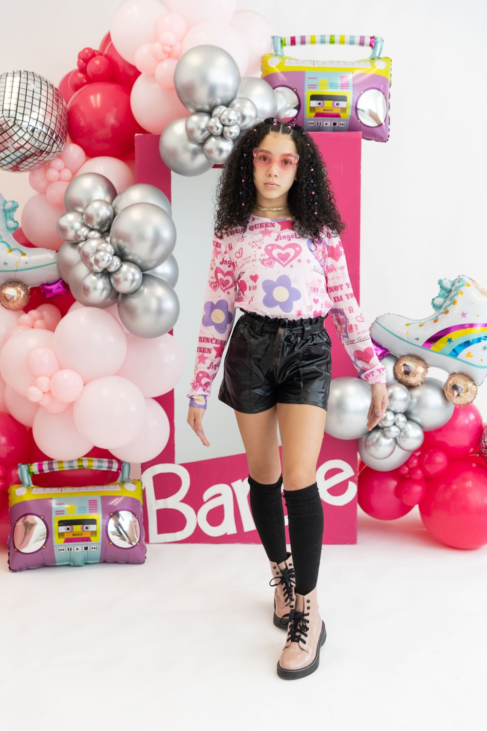 Balloon arch with pink and silver balloons creates a festive backdrop with retro boombox decorations.