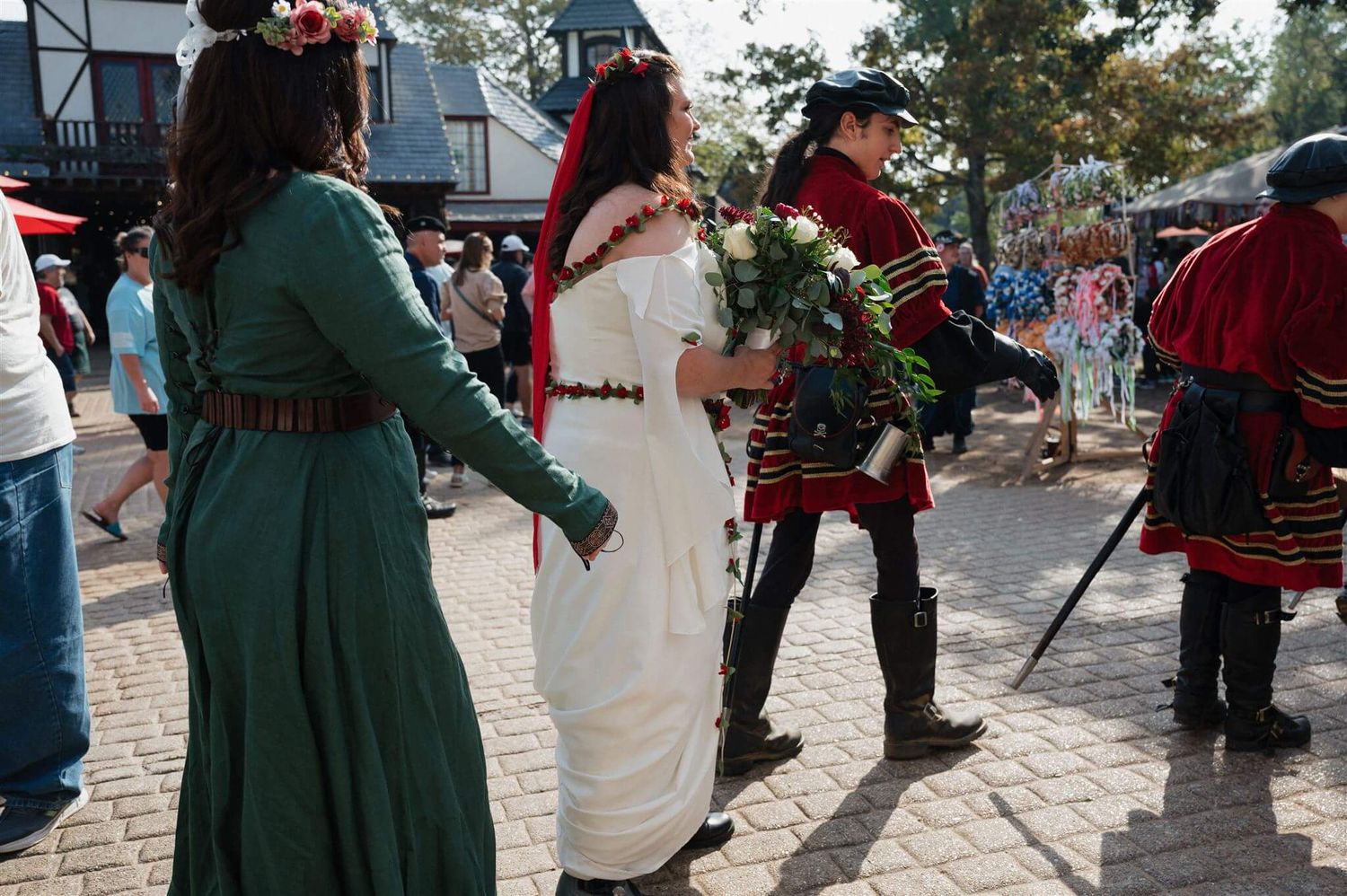 Medieval costumed performers in green and red attire dancing at a Renaissance faire.