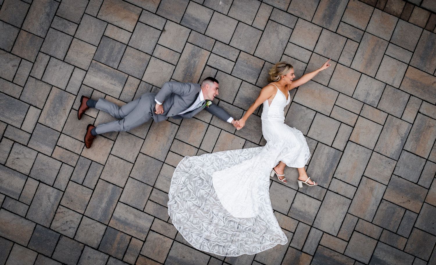 Wedding dress train flowing across decorative stone paving in artistic sequence.