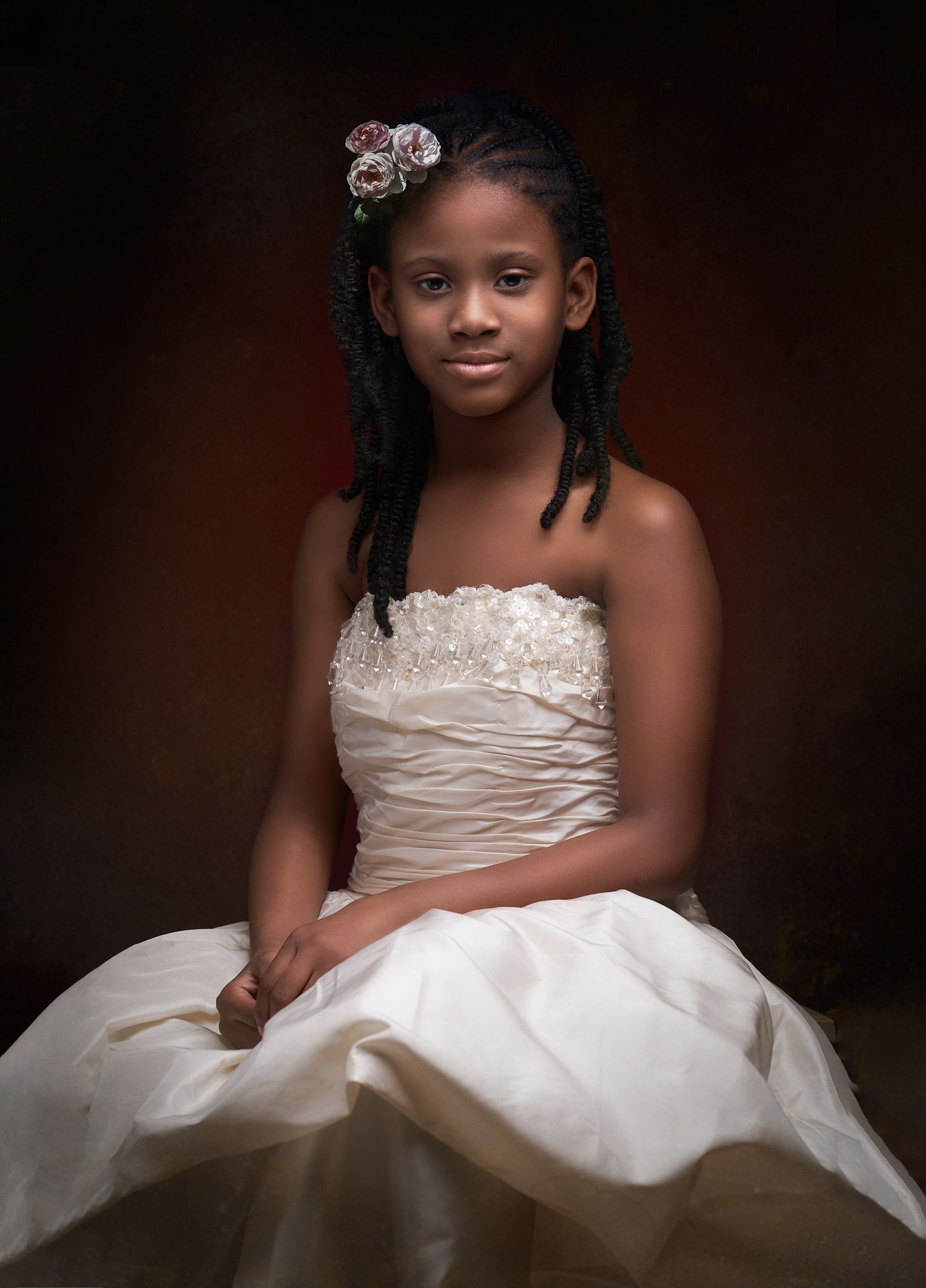 Young African American girl in a white strapless ball gown with floral hair accessories, portrait photo.