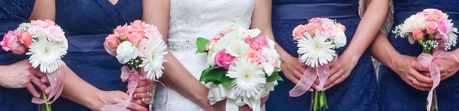 Bridesmaids in navy dresses hold pink and white bouquets.