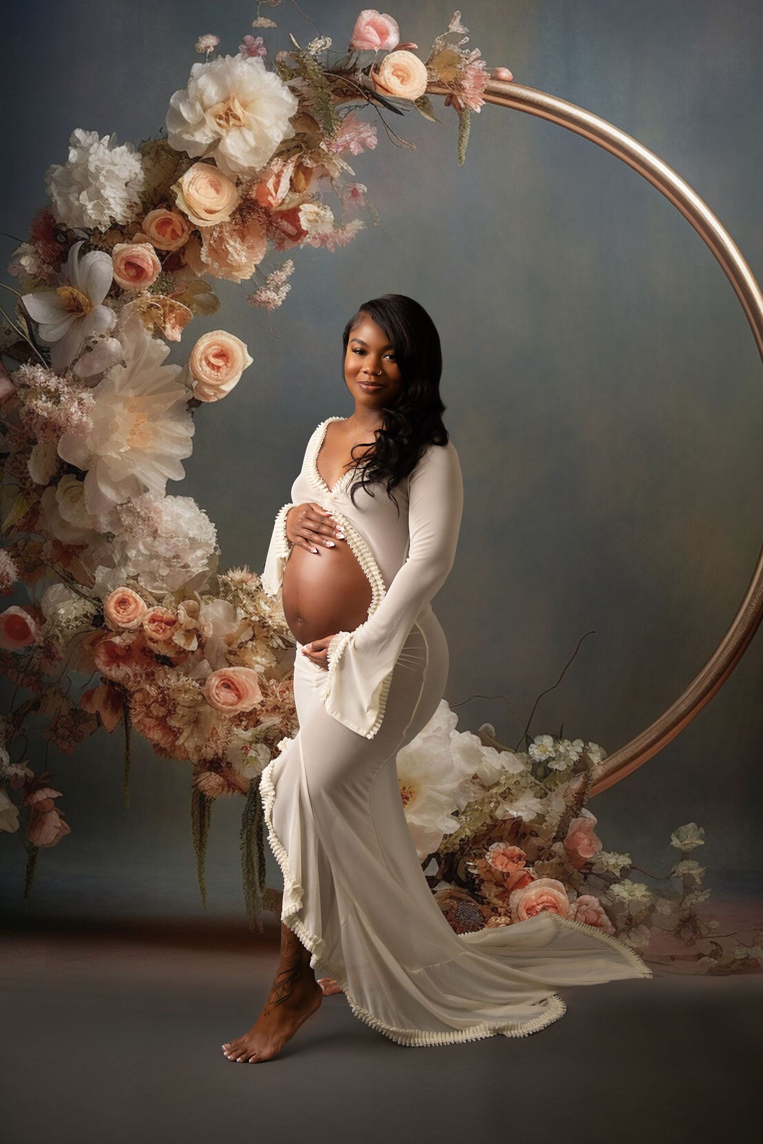 Artistic maternity photos with white gown and rose-adorned circular arch backdrop.