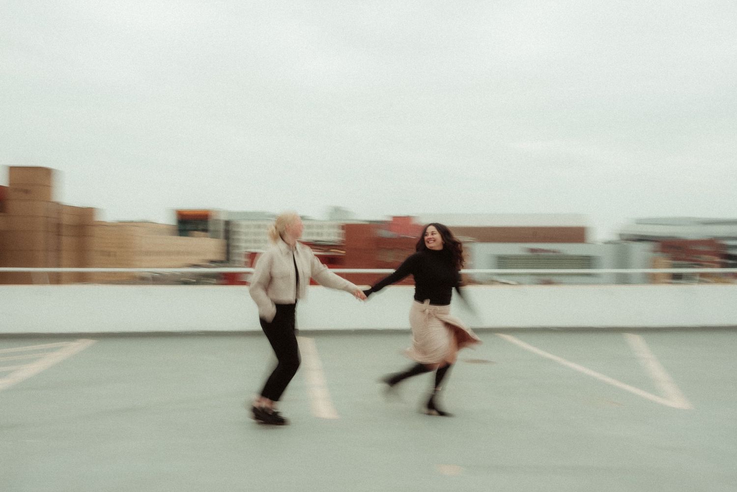 image of couple running in a parking garage outside the travelers sign in downtown des moines by iowa midwest wedding photographer