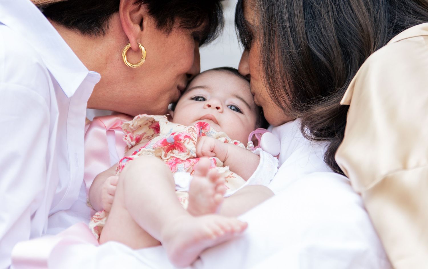 Parents sharing a loving moment with their baby in pink clothing.