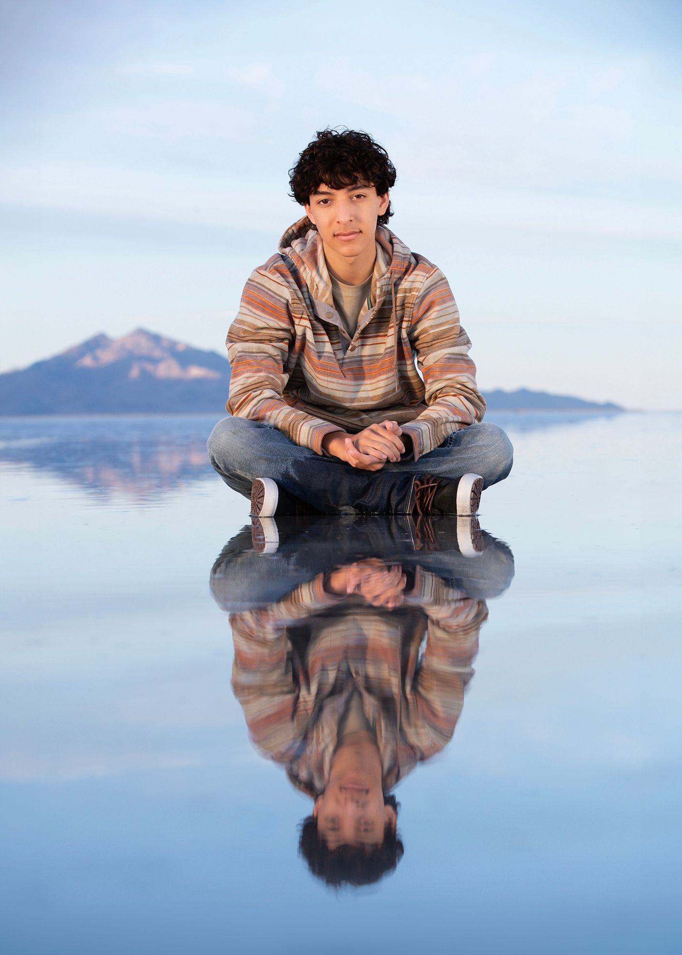 Person in striped sweater sitting cross-legged on reflective water for Bonneville Salt Flats Photography photo idea