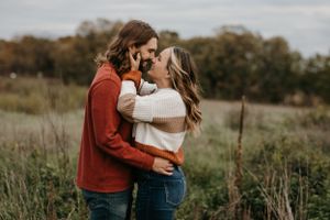 Couple embracing face to face in autumn meadow with colorful foliage background.