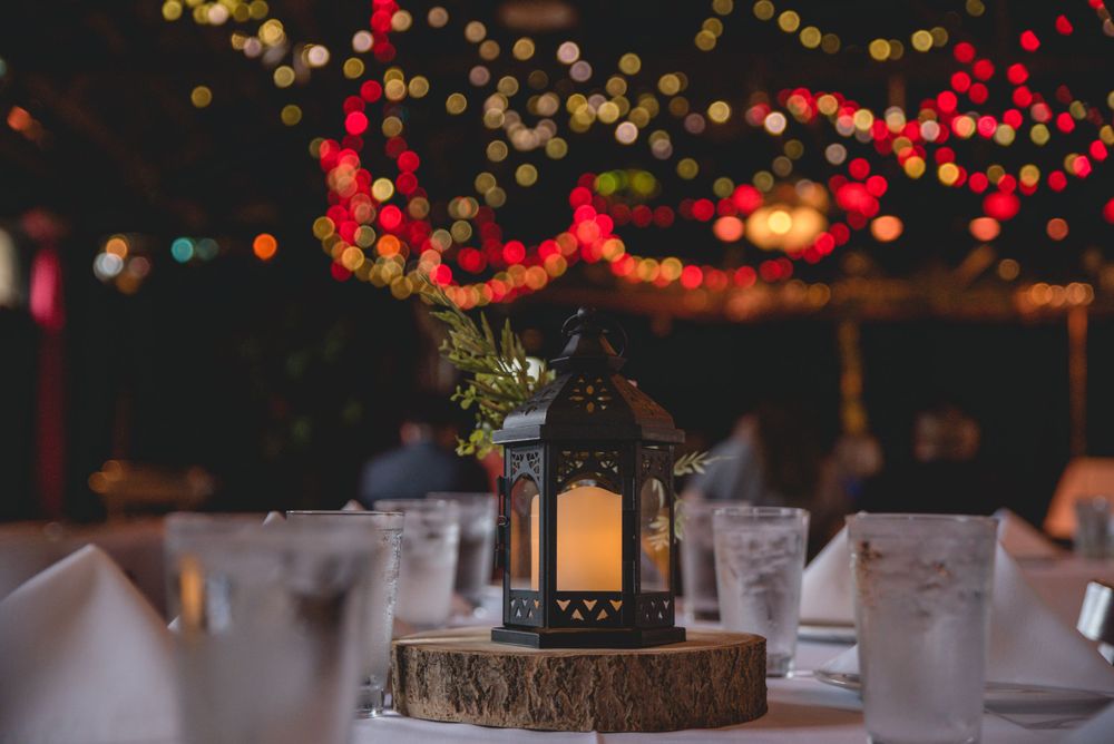 Rustic lantern centerpiece with glowing lights and bokeh effects on a wooden base.