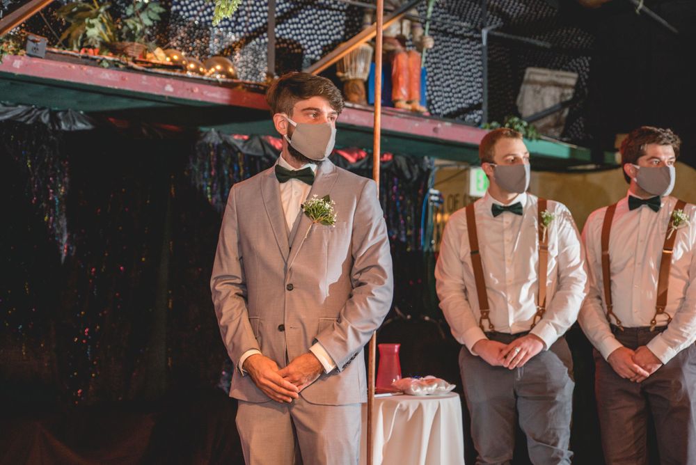 Wedding party members in gray suits and suspenders stand at attention.