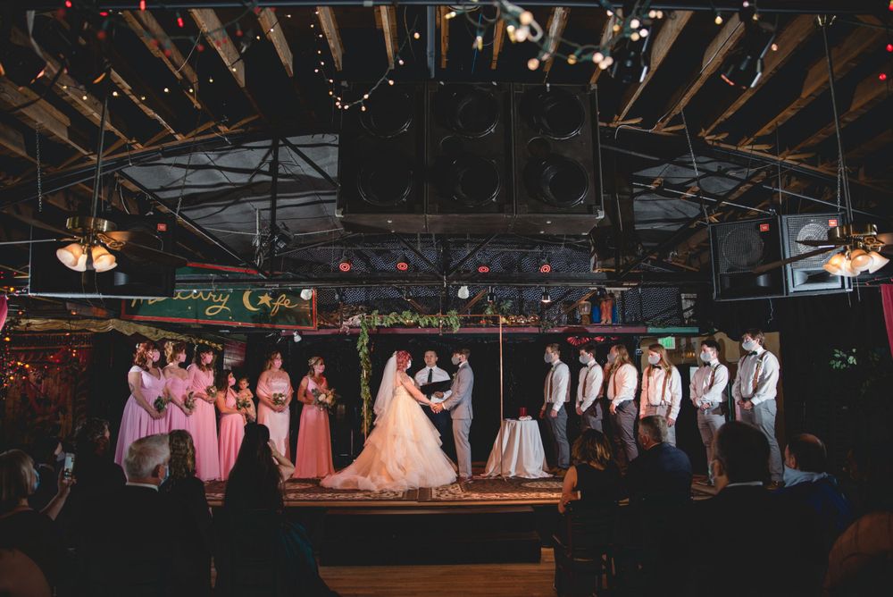 A wedding ceremony scene with bridal party lined up on stage under dim lighting.