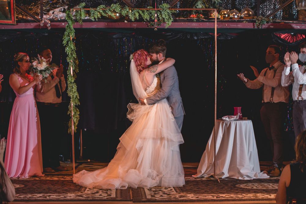 A newlywed couple shares their first dance as guests watch from the sidelines.