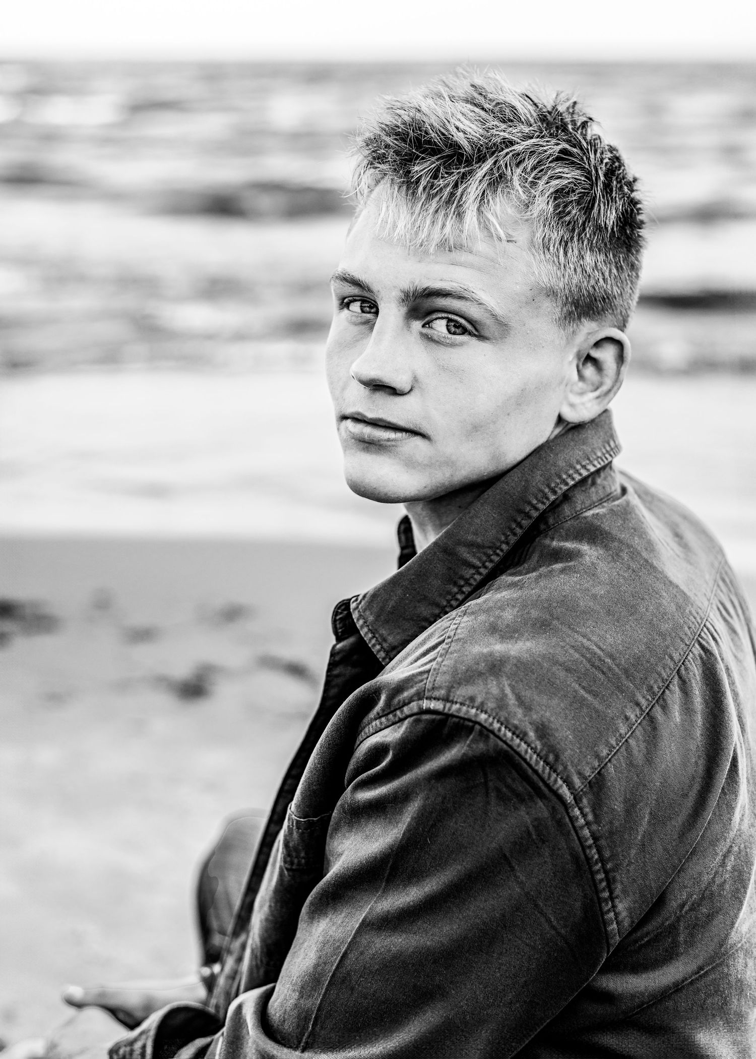 Black and white beach portrait with person in denim jacket.