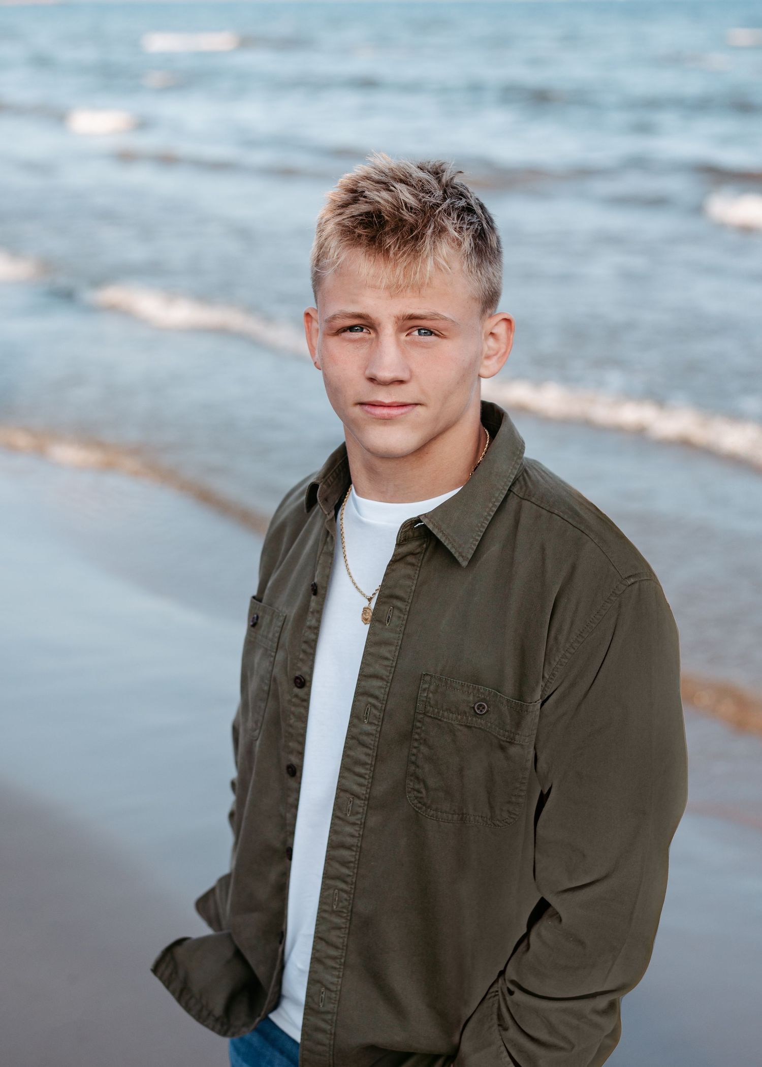 Casual portrait of person in olive jacket at beach during sunset.