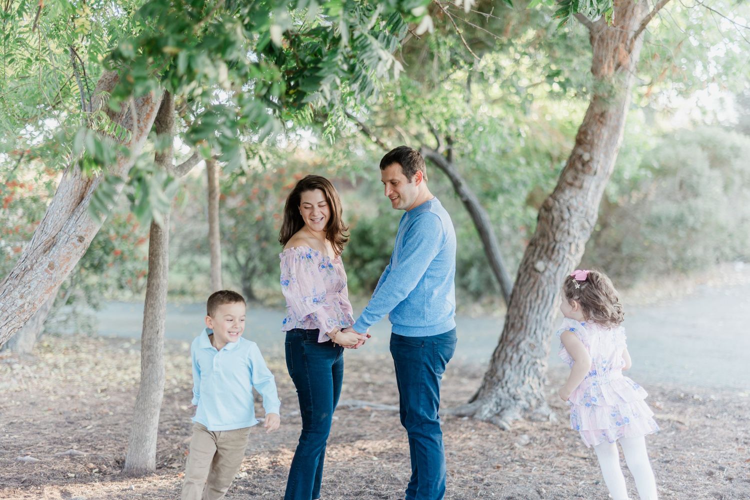 A family of four enjoying a peaceful moment together under shady trees in a park.