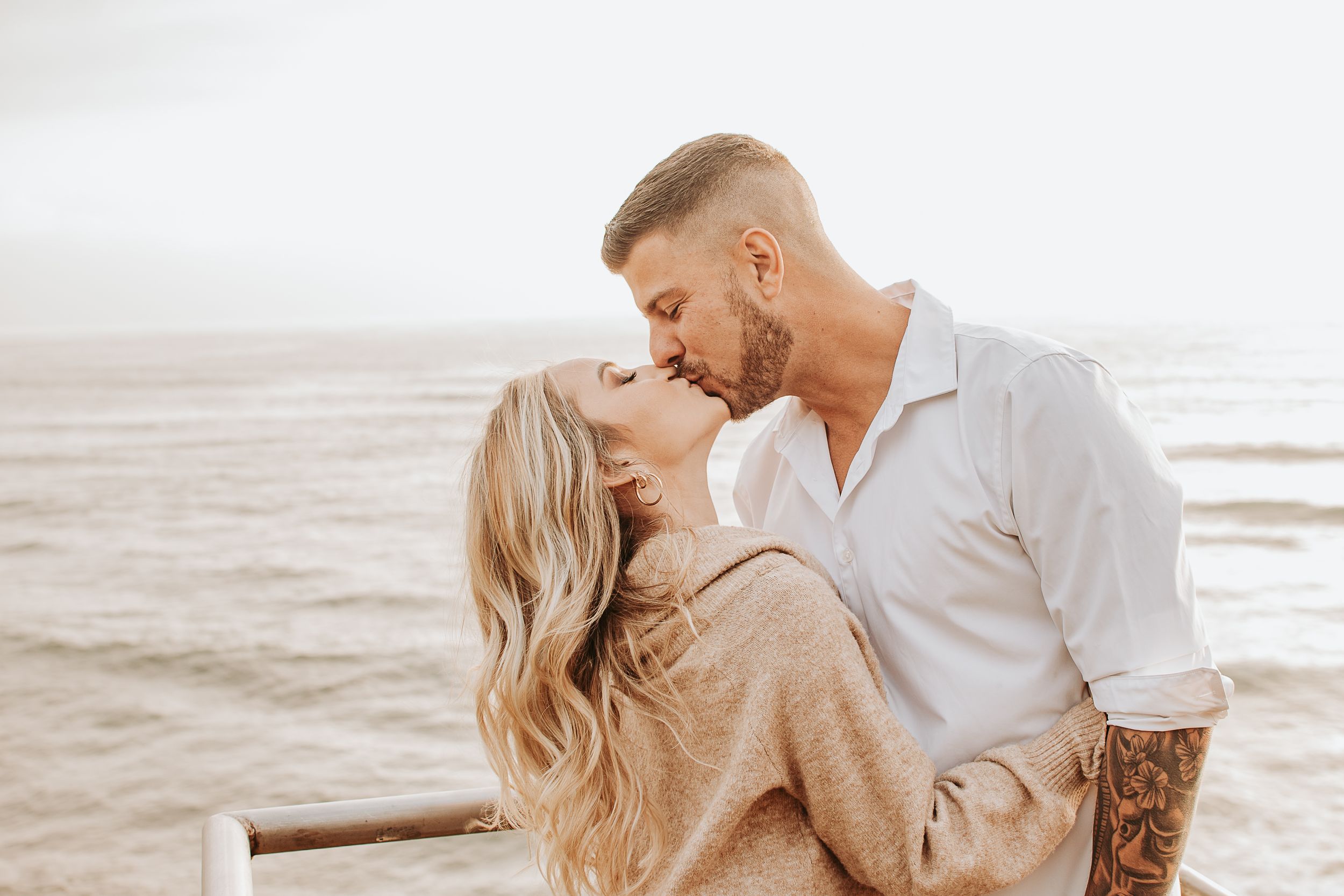 Romantic beach engagement session with couple in light colored clothing.