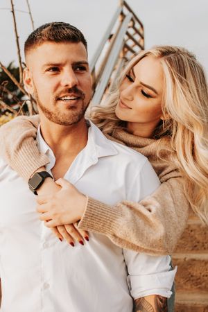 A couple in casual attire sharing an affectionate moment outdoors.
