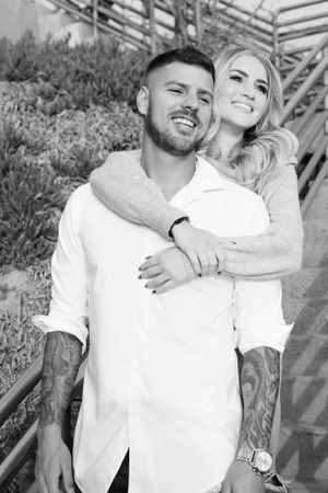 A black and white portrait of a couple smiling on wooden stairs.