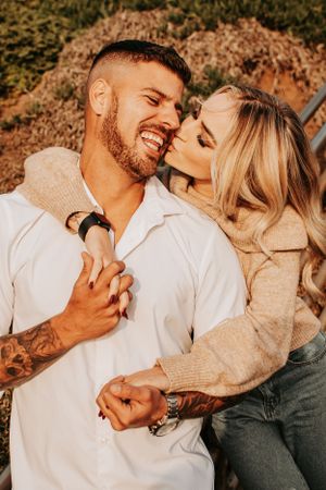 Intimate couple in casual attire sharing romantic moments against warm outdoor backdrop.