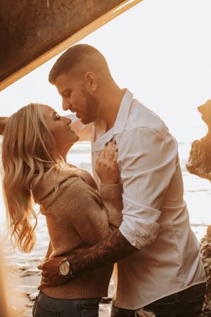 Romantic sunset photoshoot featuring couple in warm embrace by the ocean.