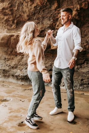 Couple dancing together against weathered rock wall backdrop.
