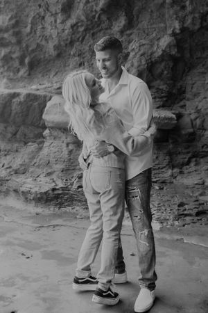 Black and white intimate portrait of couple against rocky cave wall.