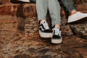 Close-up of black and white Vans sneakers on red rock formation.