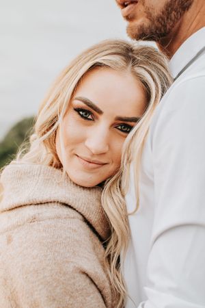 Close-up portrait with warm lighting and natural coastal backdrop.