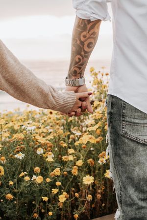 Artistic composition of hands and yellow flowers against blue denim and white clothing.