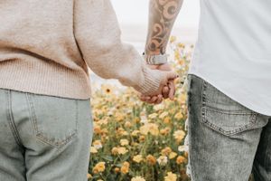 Yellow flowers blooming beside denim and sweater details in golden sunlight.