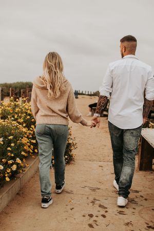 Walking together on desert path with yellow flowers and wooden fence.