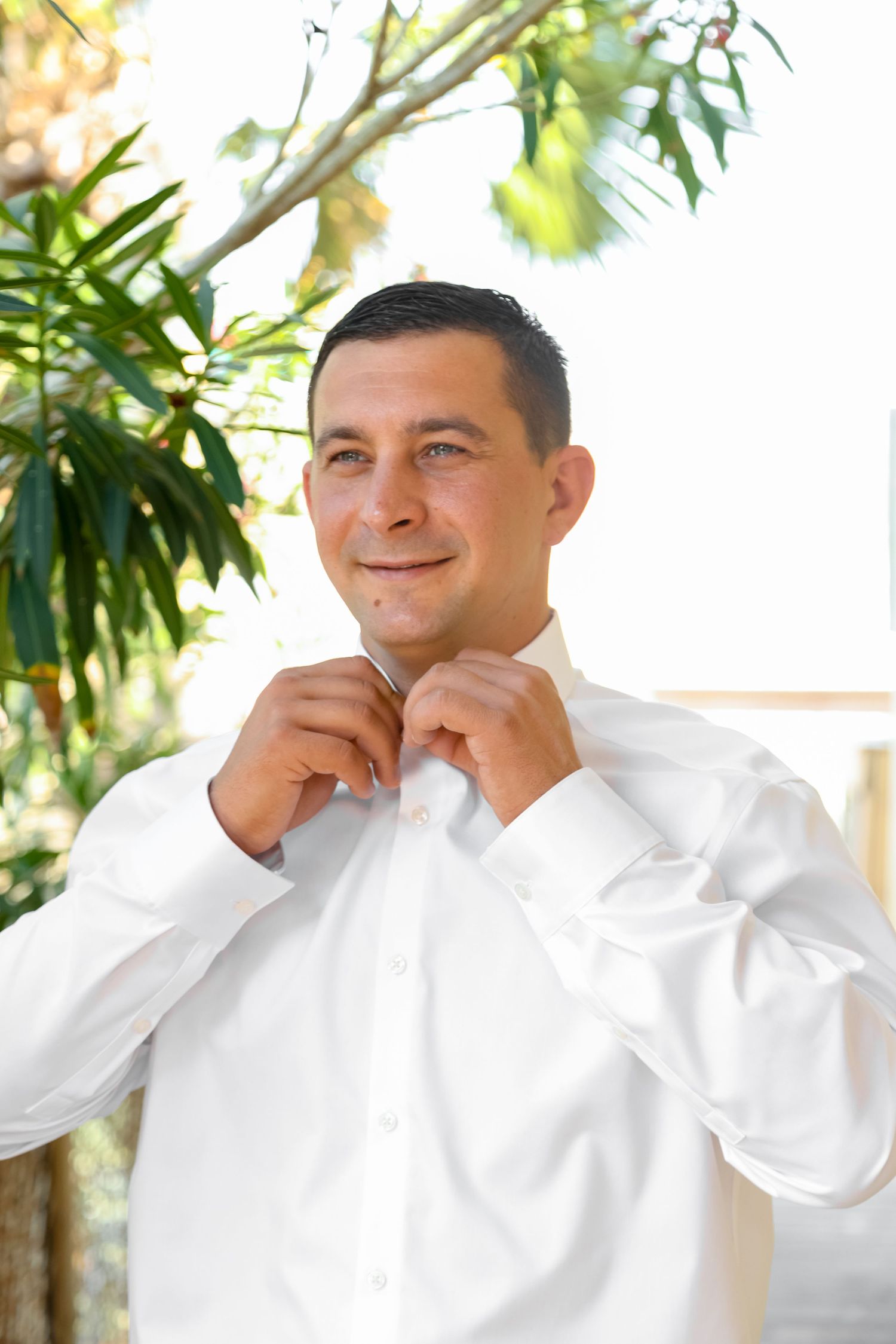 Getting ready scene with formal white attire against a tropical garden background.