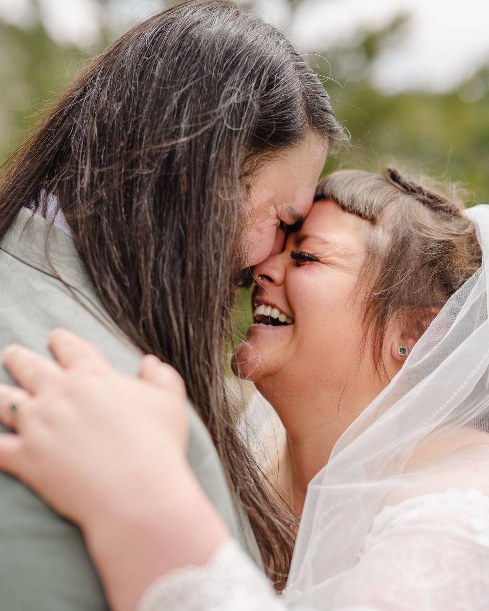 Two joyful people sharing an intimate, emotional moment with one wearing a wedding veil.