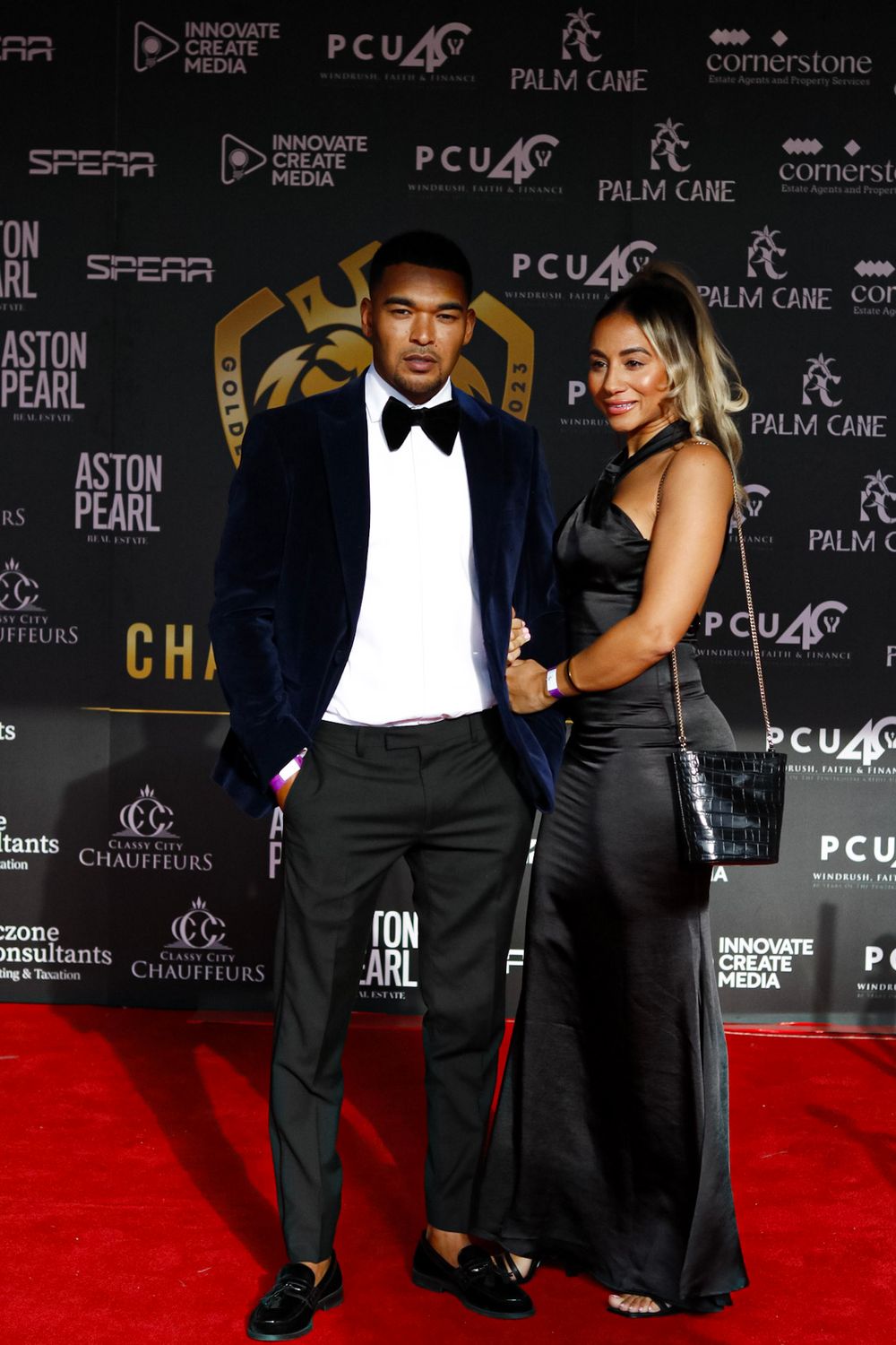 Formal event on red carpet with step and repeat backdrop featuring sponsor logos.