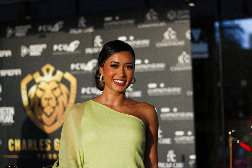 Lime green one-shoulder gown at formal event with branded backdrop.