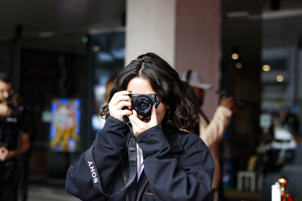 Photographer in dark clothing taking a picture with a professional camera.