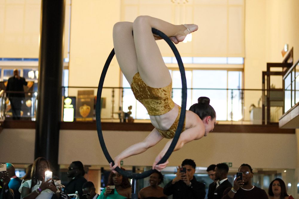 An aerial performer gracefully poses on a suspended hoop during an indoor performance.