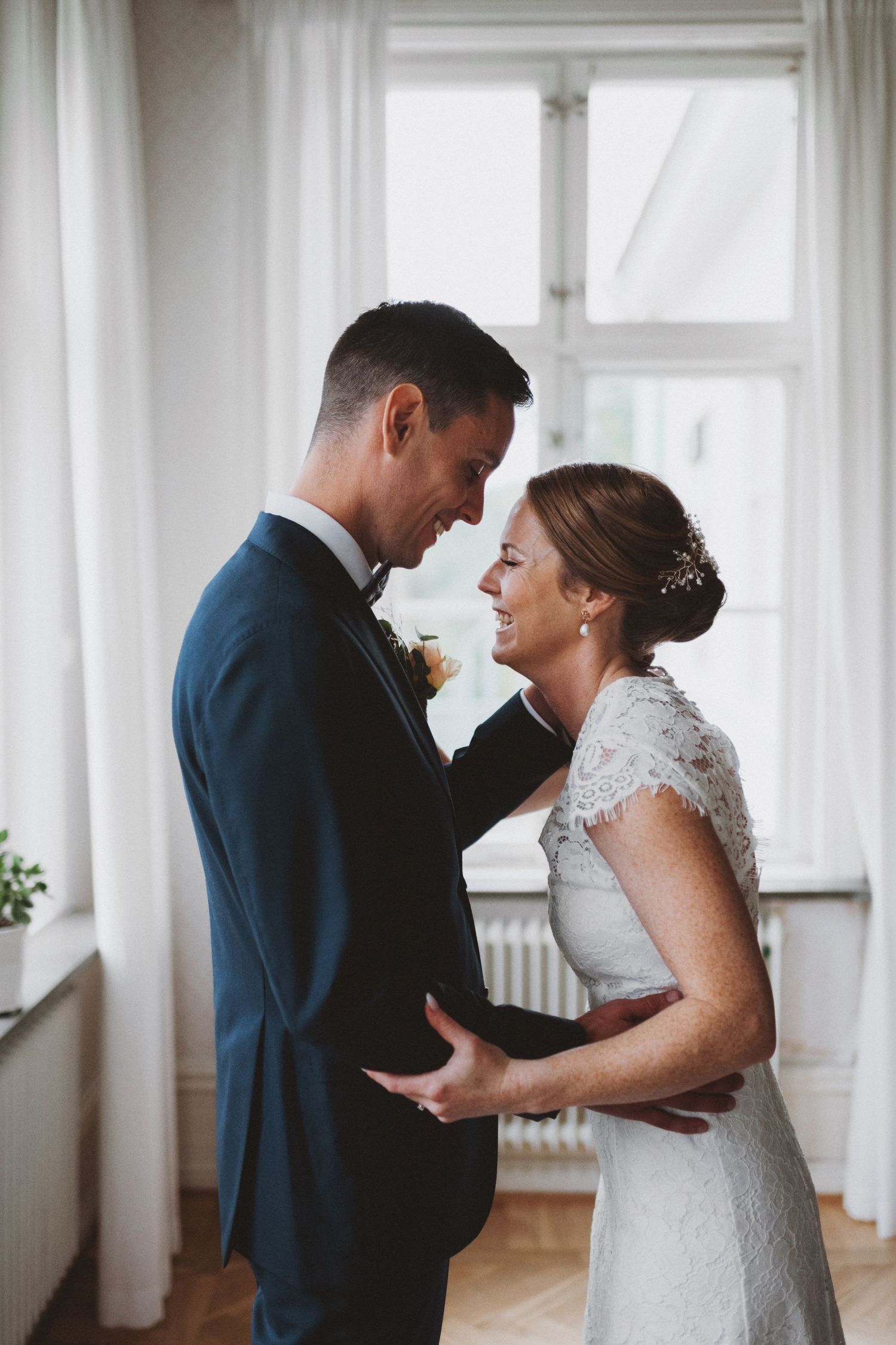 A tender wedding moment captured in a bright, airy indoor setting.