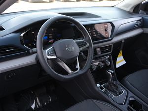 Modern vehicle dashboard with digital displays and leather-wrapped steering wheel.